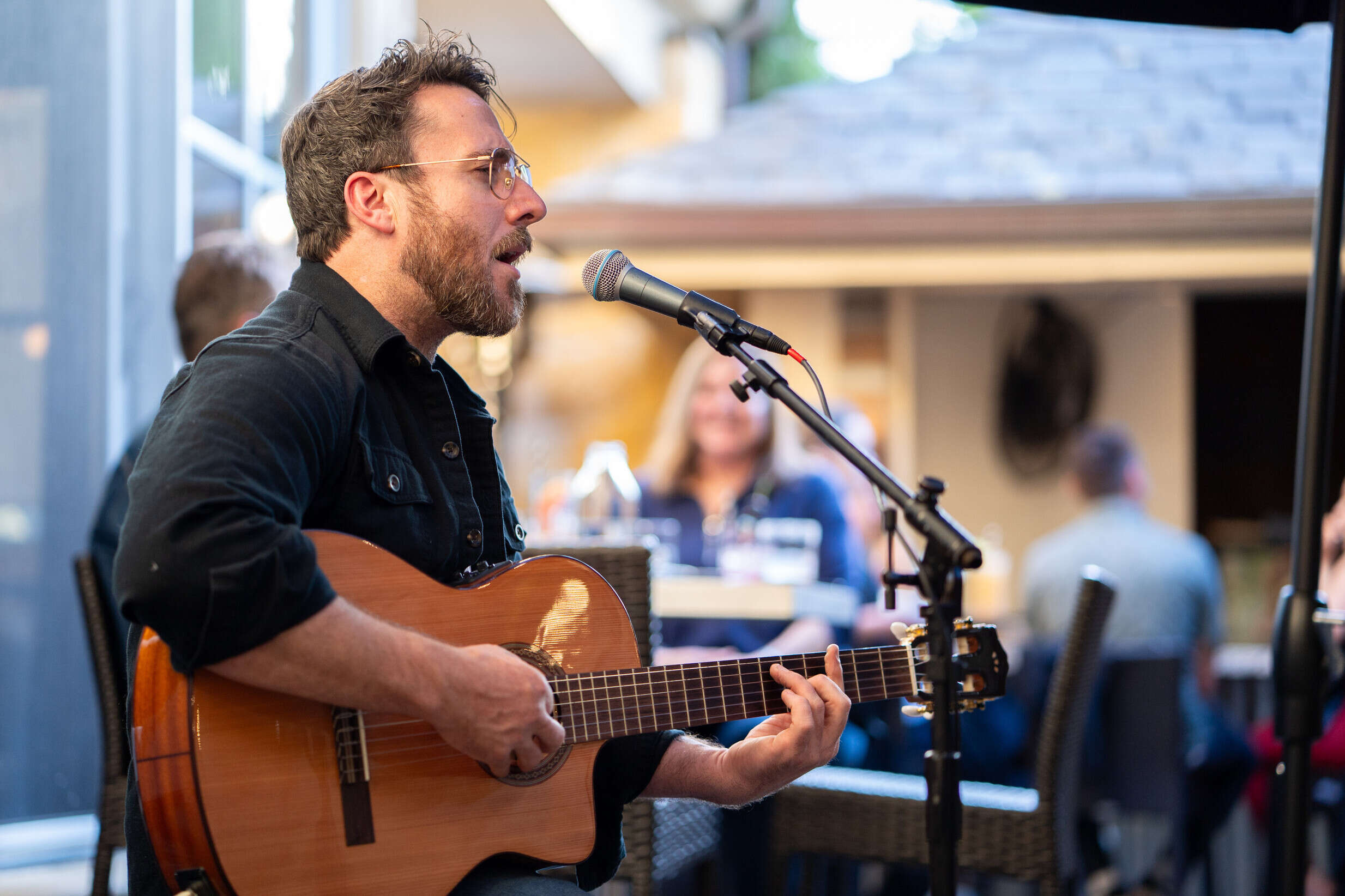 a man playing guitar and singing into a microphone